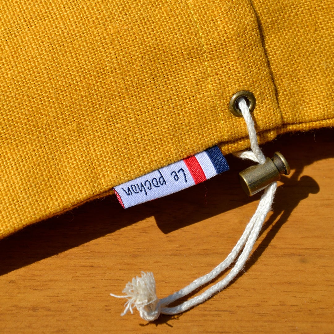 Zoom sur le tissu en lin du pochon jaune et sur son étiquette tissée