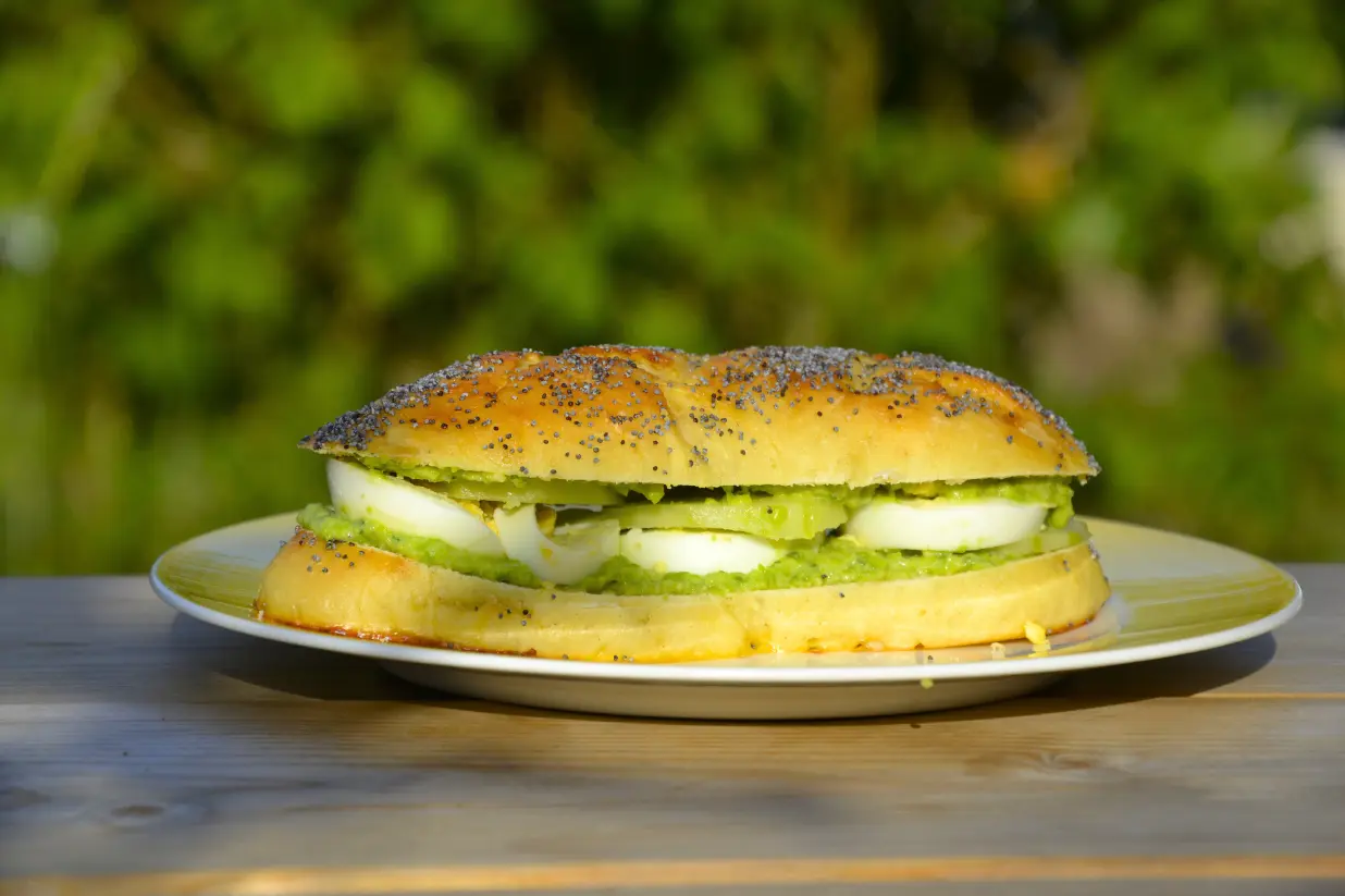 Petit pain sandwich maison, garni d'un pesto de petits pois frais, œufs durs et concombres